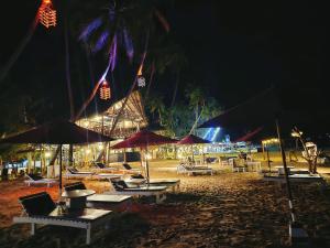 亭可马里French garden Pragash Beach Hotel的海滩在晚上提供桌子和遮阳伞