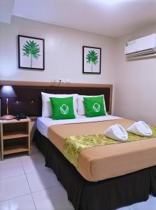 马尼拉Airport Poddotel Inc.的酒店客房配有一张带绿色枕头的大床
