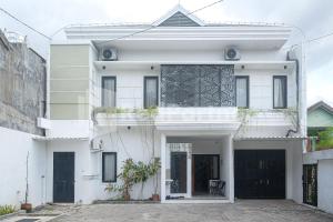 日惹Rumah Daun Timoho Yogyakarta RedPartner的白色的房子,上面有门