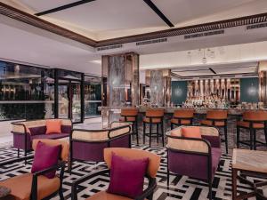 曼谷Nysa Hotel Bangkok Sukhumvit 11的一间酒吧,酒吧内摆放着紫色的椅子和桌子