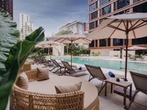 曼谷Nysa Hotel Bangkok Sukhumvit 11的一个带椅子和遮阳伞的庭院和一个游泳池