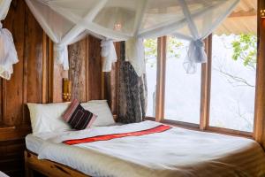 Phong ThổHoa Lan Bungalow & Restaurant的一间卧室配有一张天蓬床和窗户