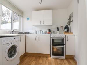 PorthallowCockle Island Cott的厨房配有白色橱柜、洗衣机和烘干机