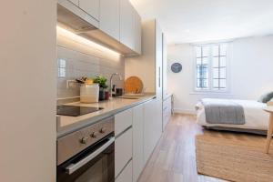 圣地亚哥Estancia Memorable en Santiago Depto Studio的厨房配有白色橱柜和一张位于底部的床。