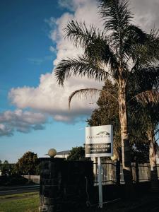 奥克兰奥克伍德庄园汽车旅馆的棕榈树前的标志