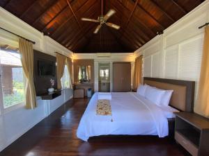 金巴兰Balangan Surf Resort的卧室配有白色的床和吊扇