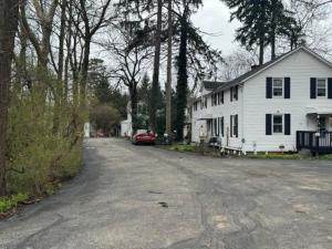 NorthfieldThe House Hotels - Acadia Farms的街上的白色房子和一辆红色汽车
