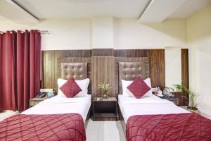 新德里RTS Hotel Delhi Airport的配有红色窗帘的酒店客房的两张床