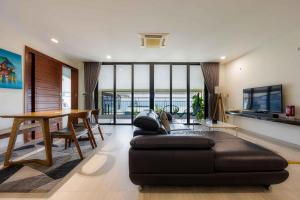 会安Beach Haven Suites Hội An Apartment的客厅配有黑色沙发和桌子