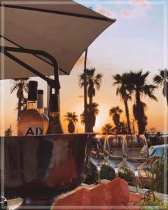特拉维夫Bugrashov Beach 88 Hotel And Spa的一张桌子、遮阳伞和椅子以及棕榈树