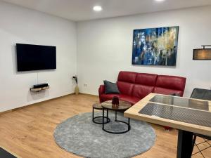 EssenRUEHOME的客厅配有红色沙发和平面电视