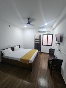 KottakupamParadise Golden Residency的卧室配有1张床、1张桌子和1把椅子