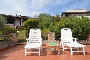 波尔托奥蒂罗卢Via dei Ciclamini - FPO-NETT01的庭院里设有两把白色的椅子和一张桌子