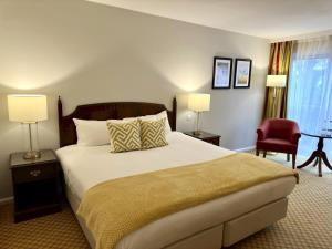 戴斯The Aberdeen Dyce Hotel的一间卧室配有一张大床和一张红色椅子