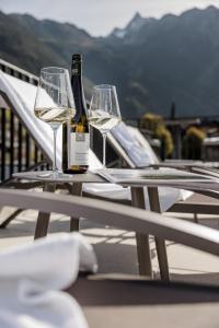 厄茨MYALPS Tirol的桌子上放着两杯酒和一瓶葡萄酒