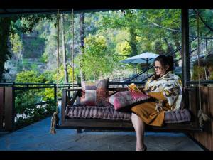 KandāghātSaffronStays Ekam Walnut Suite, Chail的坐在秋千上读书的女人
