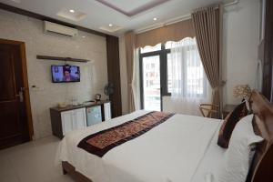 Quang BinhPhong Nha Jasmine Hostel & Roof Top Bar的一间卧室设有一张大床和一台墙上的电视。
