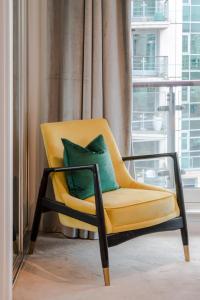 伦敦BEST THAMES VIEW in TOWN! LARGE LUXXE NOMAD DESIGN FAMILY HOME的客房内的黄色椅子和绿色枕头