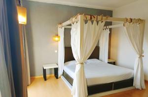 埃武拉卡萨多维尔酒店的卧室配有带白色窗帘的天蓬床