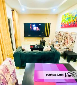 Ado EkitiLA GRANITA HOTEL AND SUITES的客厅配有绿色沙发和平面电视