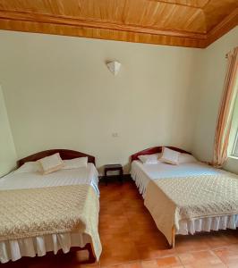 Dong QuanNew Sky Hotel的配有白色墙壁和木制天花板的客房内的两张床
