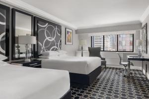 纽约The Muse New York的酒店客房配有两张床和一张书桌
