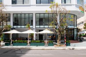 岘港PĀMA Boutique Hotel & Bistro的前面有桌子和伞的建筑