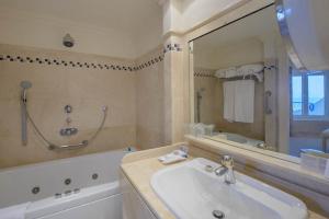 加的斯维多利亚海滩酒店的一间带水槽、浴缸和镜子的浴室
