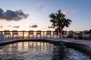 菲罗斯特法尼Mill Houses New Elegant Suites的一个带椅子的游泳池,享有日落美景