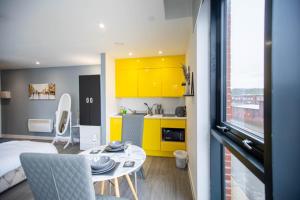 谢菲尔德New studio balcony apartment in Sheffield的一间厨房,里面配有黄色橱柜和一张桌子