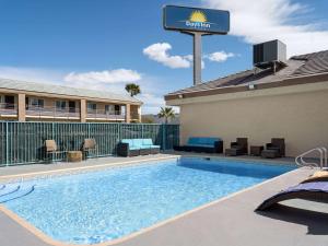 拉斯维加斯Days Inn by Wyndham Las Vegas Airport Near the Strip的一座带椅子的游泳池,旁边是一座酒店标志