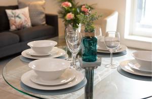 都柏林GuestReady - Beautiful apartment on Dublin Coast的玻璃桌,上面有盘子和酒杯