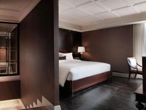 曼谷美憬阁曼谷缪斯廊双酒店的一间卧室配有一张床和一把椅子