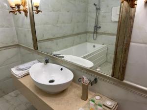 阿克托比Royal的浴室配有盥洗盆、镜子和浴缸