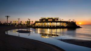 贝鲁特贝鲁特萨默兰凯宾斯基度假酒店的海滩上的建筑,背面是日落