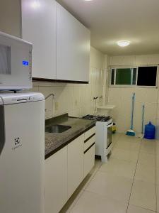 加拉尼温斯Apartamento Lótus Ar Cond Pertinho FIG e Centro的厨房配有白色橱柜和水槽