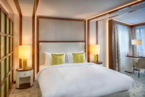 布达佩斯布达佩斯科维努斯凯宾斯基酒店的卧室配有一张白色大床和两盏灯。