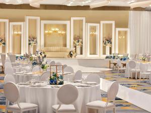 马斯喀特Mövenpick Hotel & Apartments Ghala Muscat的宴会厅配有白色的桌子和白色的椅子