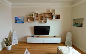 热那亚Mare Monti的一间客厅,客厅的白色橱柜上配有电视