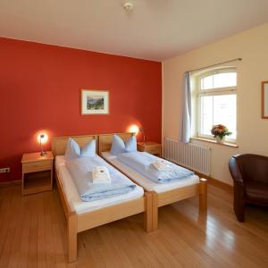 Creuzburg斯提夫沃尔姆生态酒店的一间卧室设有两张床和红色的墙壁