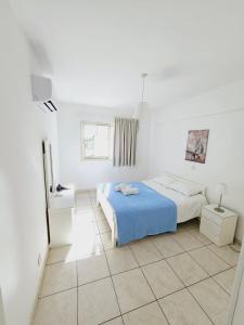 拉纳卡斯蒂芬妮城市公寓的白色卧室设有蓝色的床和窗户