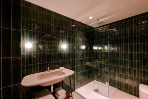 莱斯比Laceby Manor - Spa & Golf Resort的黑色瓷砖浴室设有水槽和淋浴