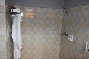 YumbeESCAPE VILLAGE HOTEL的配有白色浴袍和淋浴的浴室