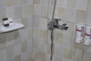 YumbeESCAPE VILLAGE HOTEL的瓷砖浴室内带软管的淋浴