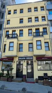 伊斯坦布尔Galata Dream Hotel的黄色的建筑,上面标着读卡拉加梦的标志
