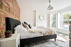 伦敦The Perfect Retreat-3 bedroom garden with Hot Tub的一间卧室设有一张床和砖墙