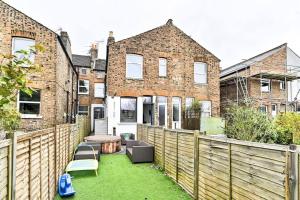 伦敦The Perfect Retreat-3 bedroom garden with Hot Tub的后院设有木栅栏和桌椅