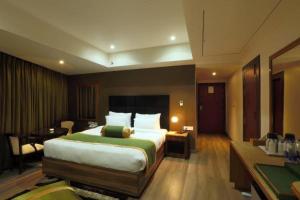 古瓦哈提HOTEL SHOOLIN GRAND的酒店客房设有一张大床和一张书桌。