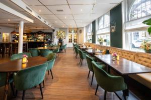 诺德韦克皇家酒店的餐厅设有木桌和绿色椅子