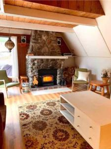 梅戈格Le Rustique Orford Domaine Cheribourg的客厅设有石制壁炉、椅子和桌子